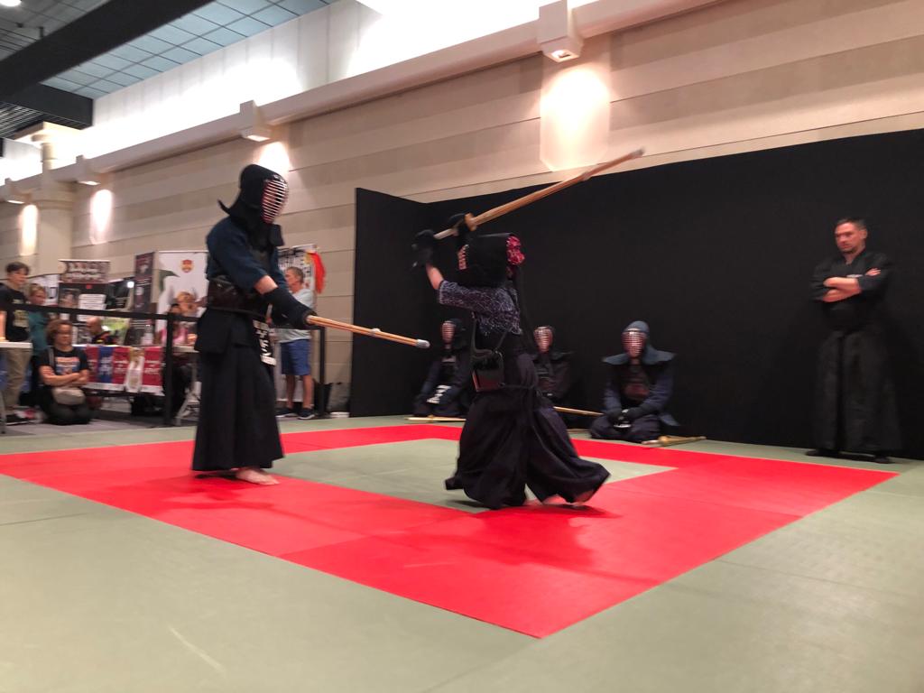 Enfant pratiquant le kendo en armure face à un autre combattant.
